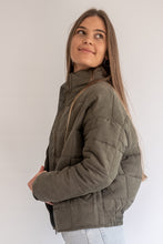 Load image into Gallery viewer, Woman wearing a green quilted jacket against a white background
