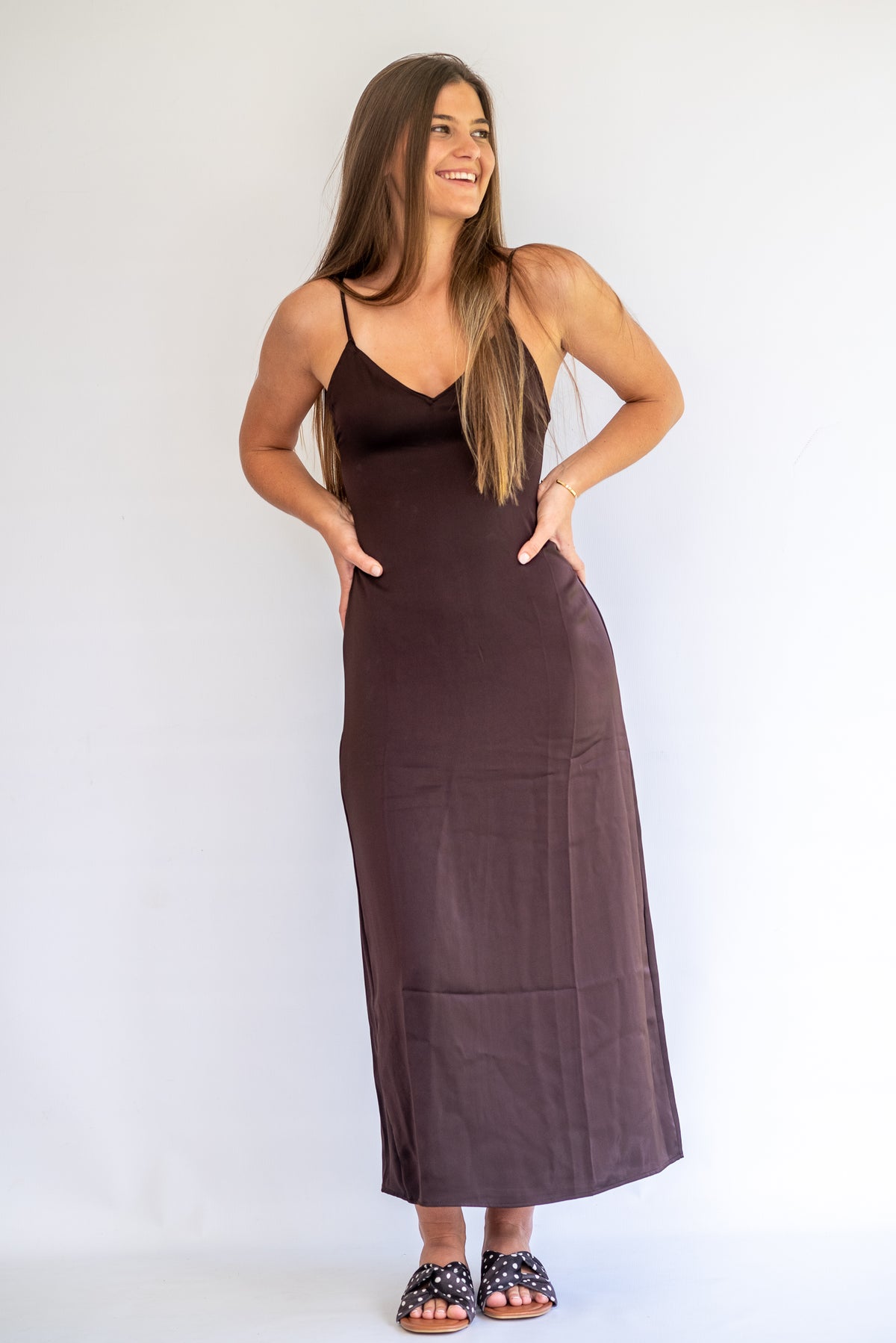Woman wearing a brown slip dress against a white background