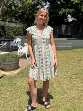 Load image into Gallery viewer, Woman wearing a green and pink palm and shell patterned dress standing in a garden.
